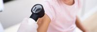 Dermatologist uses diagnostic tool to examine child's arm.